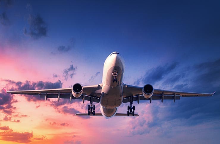 An airplane flying against a sky with a sunset.